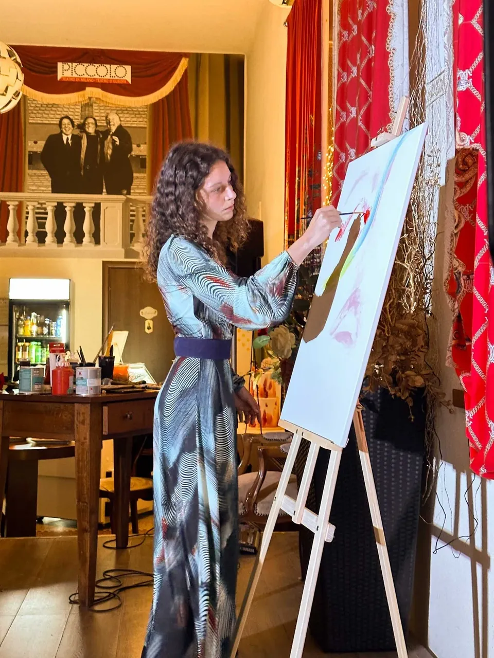 Giulia Dal Bon dipinge su tela in una sala ricevimenti, durante l’evento