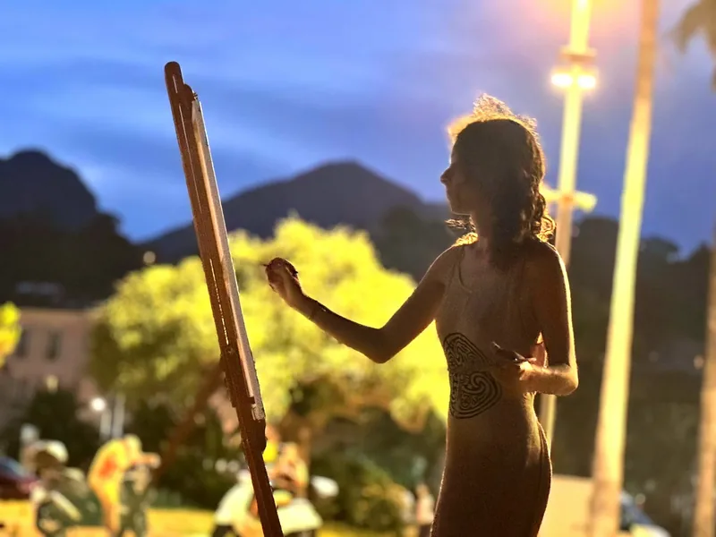 Esempio di live painting a Mentone: di notte, in riva al mare, Giulia Dal Bon dipinge al cavalletto alla luce dei lampioni.