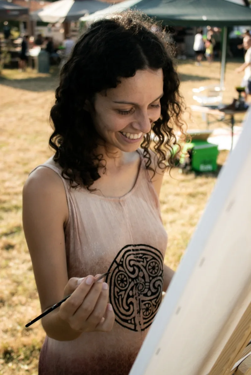 Live painting a Parigi: all’aperto, Giulia Dal Bon dipinge dal vivo, sorridente, davanti al cavalletto.