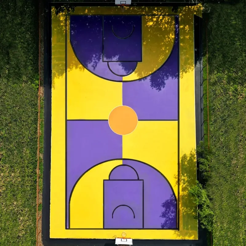 Giulia Dal Bon a repeint un terrain de basket en grands aplats jaunes et violets, ici vu du ciel.