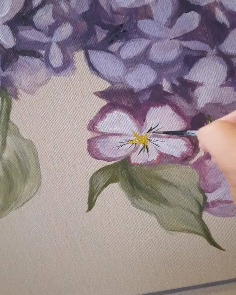 Esempio di murale di fiori interamente dipinti: Giulia Dal Bon dipinge a pennello una viola del pensiero tra i lillà.