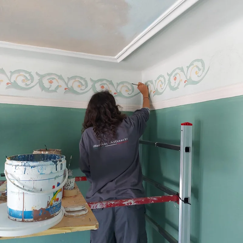 Ejemplo de mural en Pisa: bajo la cornisa de una habitación, Giulia Dal Bon hace correr un friso pintado.