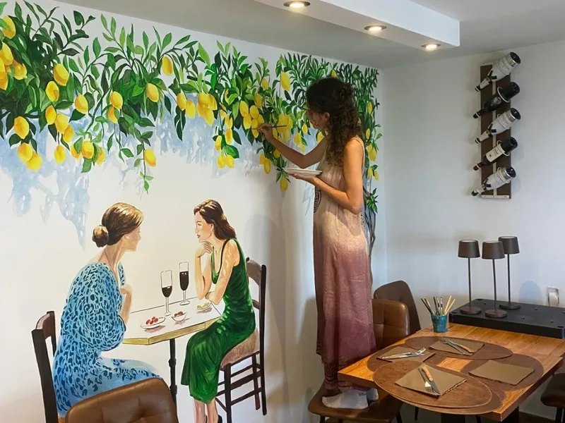 Ejemplo de mural en Córcega: Giulia Dal Bon pinta a pincel los limoneros de un restaurante.