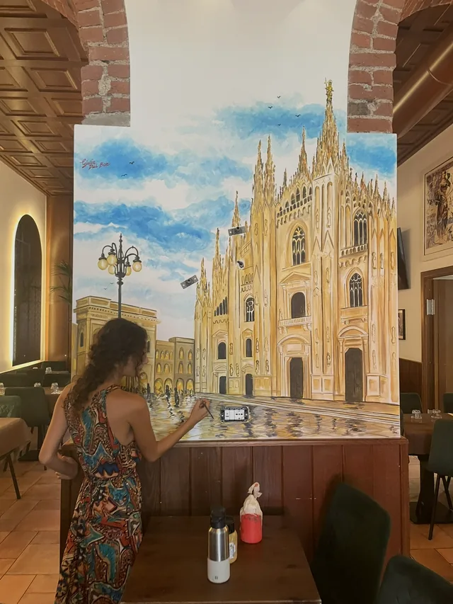 Giulia Dal Bon reprend au pinceau les détails du Duomo de Milan, sur la fresque qu’elle a peinte dans un restaurant milanais.