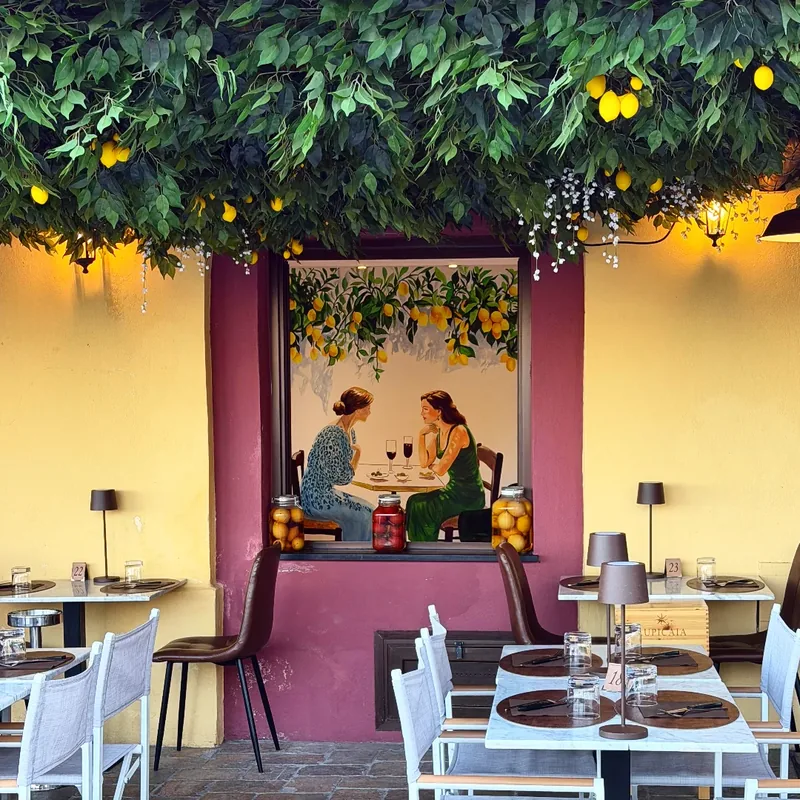 Ejemplo de mural en Arlés: Giulia Dal Bon pintó a dos mujeres cenando bajo un limonero. El mural en trampantojo se funde a la perfección con el ambiente del restaurante.