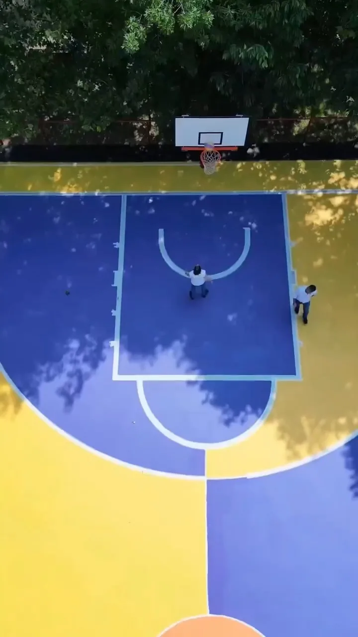 Sur le terrain de basket repeint par Giulia Dal Bon, deux joueurs se retrouvent sous le panier.
